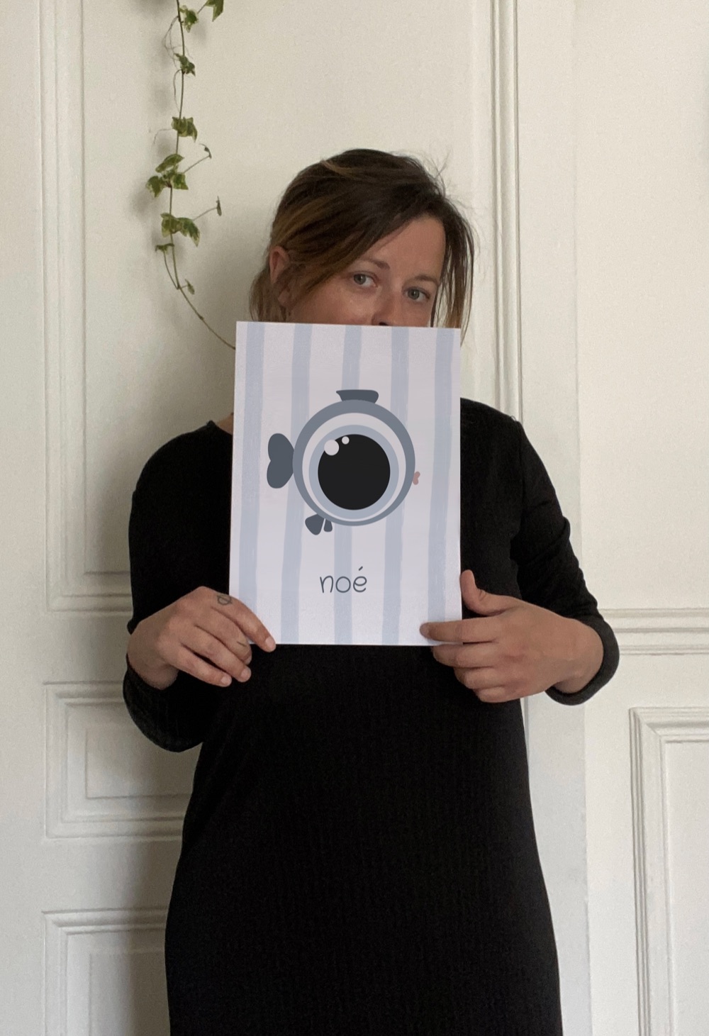 La créatrice de MINÖT tenant l'affiche noé le poisson